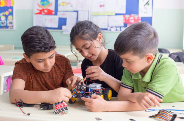 Three students working together to build a wheeled robot.